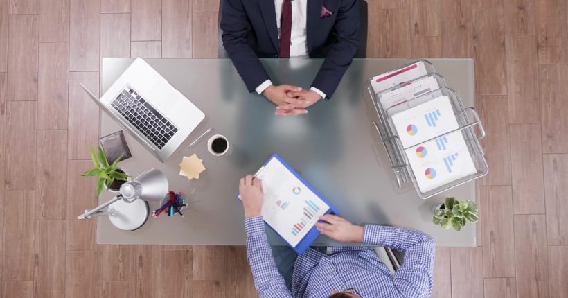 Top view of businessman analyzing financial documents discussing company strategy Top view of businessman analyzing financial documents discussing company strategy with partner during partnership meeting in startup office. Colleagues planning business strategy. Corporate agreement